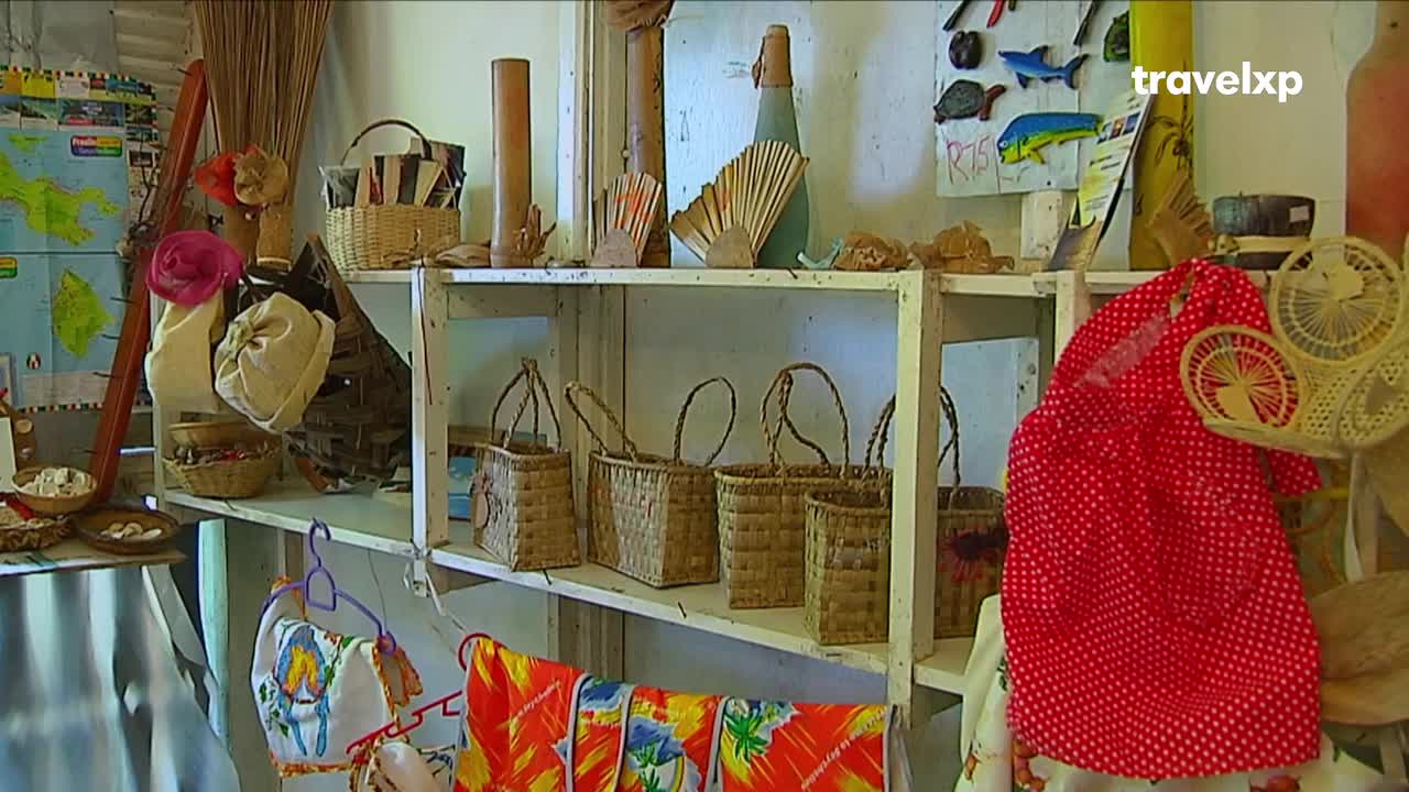 A row of woven baskets sits on a shelf, their handles reaching upward. Nearby, a bright red polka-dot dress hangs, its fabric catching the light.