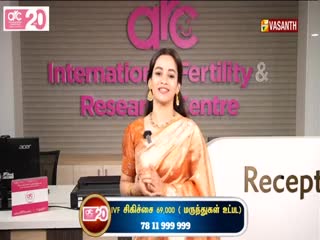 A woman in a peach-colored sari smiles at the camera, standing in front of a sign for a fertility clinic. Below her, a graphic on Vasanth TV displays the cost of IVF treatment.
