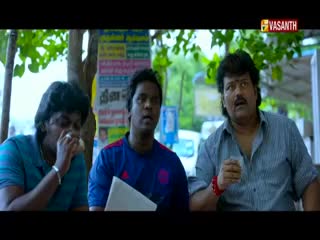 A man in a blue shirt holds a cigarette to his mouth while the others look on, one with a glass in his hand. The Vasanth TV logo is in the corner, and there's a sign with Tamil writing behind them.
