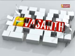 The Vasanth TV logo, a red rectangle with white letters, is emerging from a fragmented block structure. The top right corner shows the Vasanth logo in a smaller, rectangular form.
