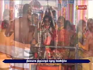People are gathered, some with their hands raised, in front of a decorated idol. The Vasanth TV logo is visible, and a banner with Tamil text runs along the bottom.
