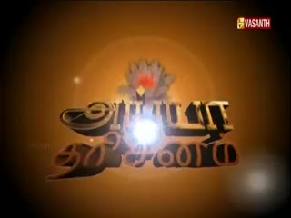 The Vasanth TV logo, rendered in a 3D style, shines brightly against a warm orange background. The Tamil script appears to be the focus, with a lotus flower and a bright light source at the center.
