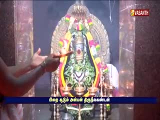 A brightly adorned idol stands in a temple, lit by lamps. A hand gestures toward the deity, while a Vasanth TV logo appears in the corner.
