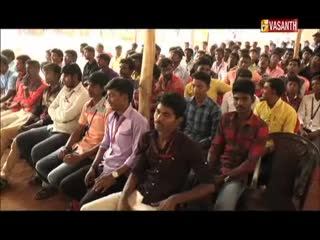A large crowd of men sits in rows, many wearing button-down shirts and looking forward. The Vasanth TV logo is visible in the corner.
