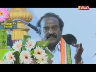A man with a mustache speaks into a microphone, gesturing with his right hand. The Vasanth TV logo is visible in the corner.
