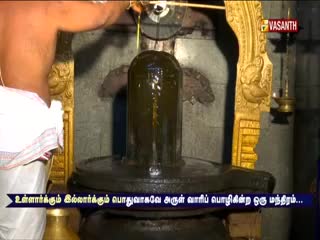 A priest is pouring liquid over a dark, cylindrical structure, the water cascading down its surface. The Vasanth TV logo sits in the corner, broadcasting the ritual from India.
