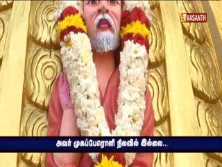 A garland of white flowers, accented with red and yellow, frames the figure's face. The Vasanth TV logo sits in the top right corner, and a blue banner with Tamil text appears below.
