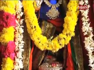 A thick garland of yellow flowers hangs around a figure draped in red and dark fabric. The Vasanth TV logo is visible in the top right corner, and the broadcast is clearly from India.
