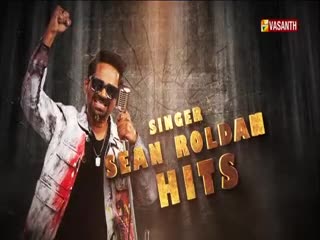 Sean Roldan, the singer, holds a microphone and raises his fist, looking energetic. The Vasanth TV logo is in the corner, and the words "Sean Roldan Hits" are displayed in gold.
