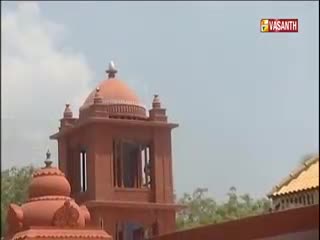 A terracotta-colored building with a domed roof stands under a hazy sky, the Vasanth TV logo visible in the corner. The architecture looks distinctly Indian, with a smaller dome in the foreground.
