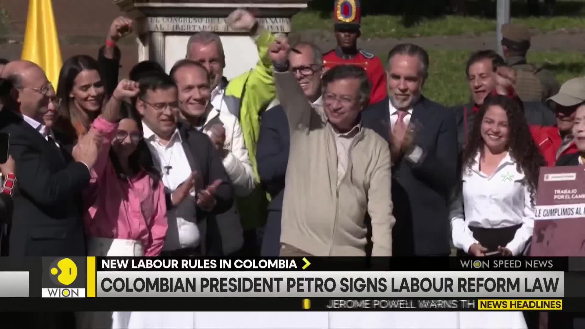 President Petro, wearing a light sweater, raises a fist in the air, surrounded by a cheering crowd. The WION news banner below announces the signing of a labor reform law.
