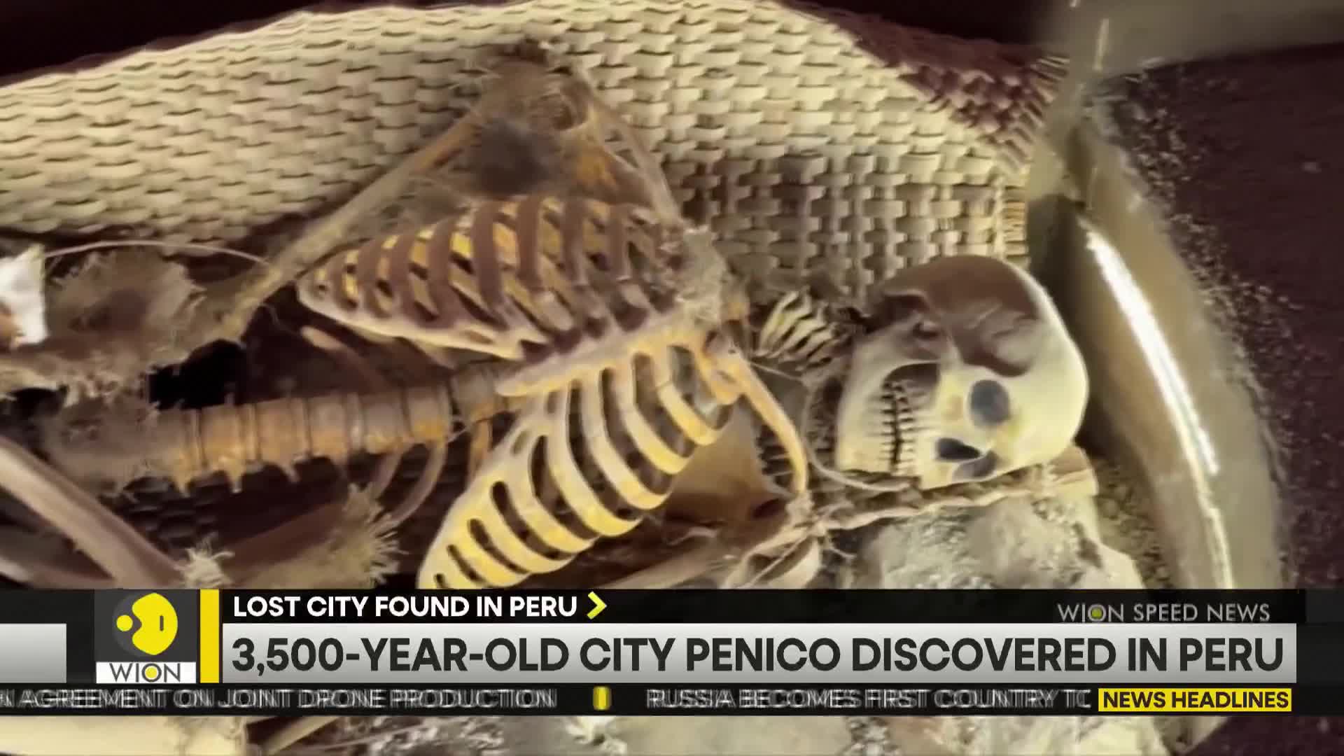 A human skeleton lies in a dark enclosure, its ribcage and skull clearly visible. The news ticker at the bottom of the screen from WION announces the discovery of a 3,500-year-old city in Peru.
