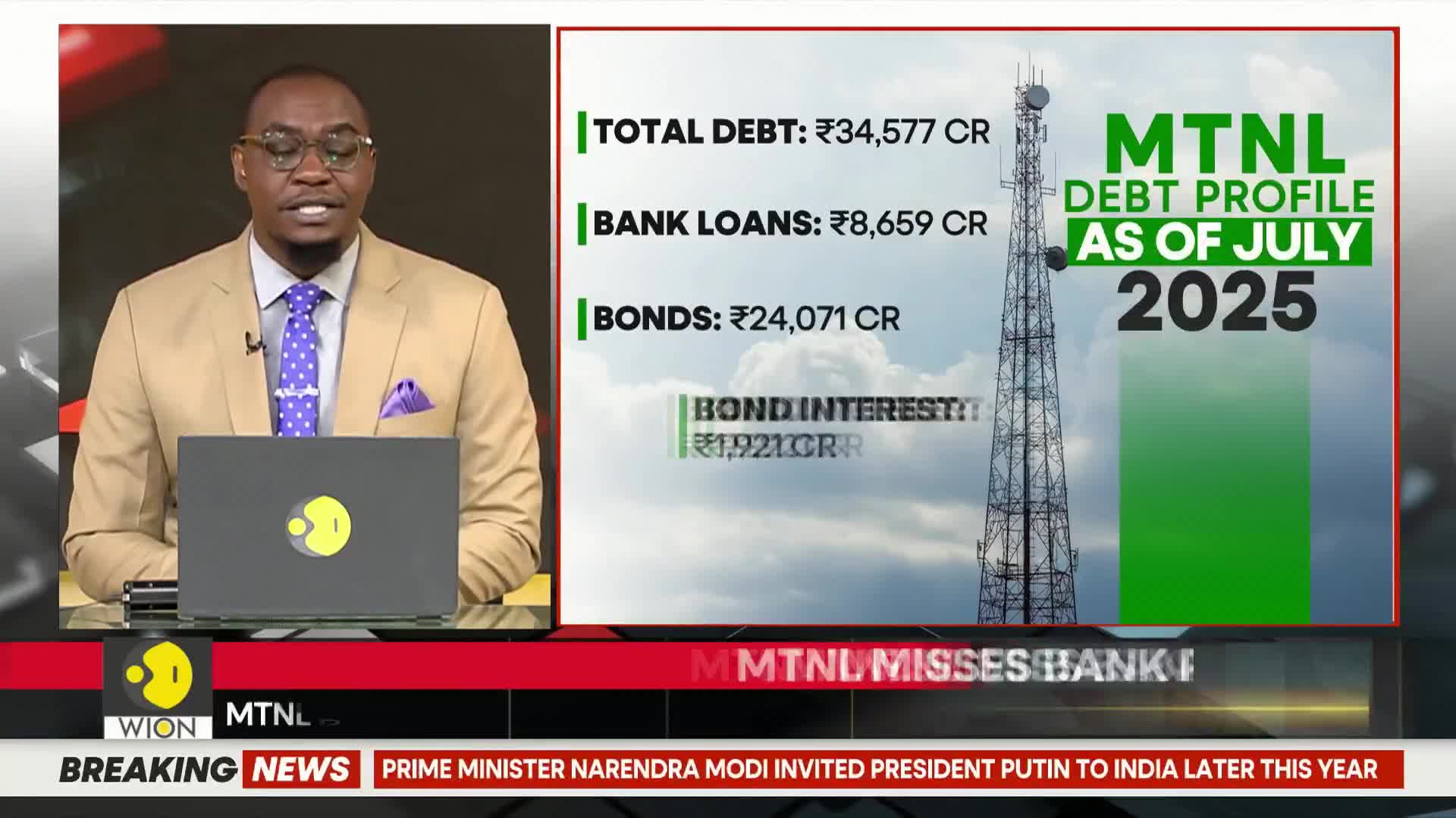 A news anchor, wearing a tan jacket and a patterned tie, speaks from behind a desk. On the screen, financial data from India is displayed, along with a graphic of a communications tower.
