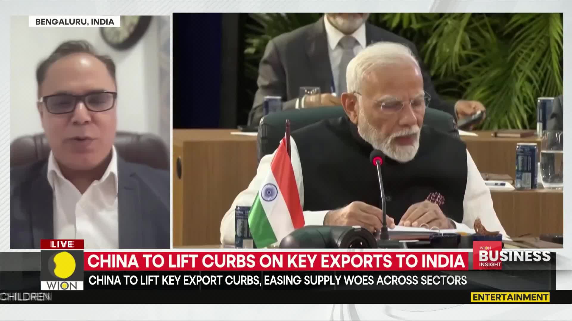 A man in Bengaluru, India, appears on a screen, while the Prime Minister of India sits at a table, a small Indian flag in front of him. The WION news segment focuses on China lifting export curbs.
