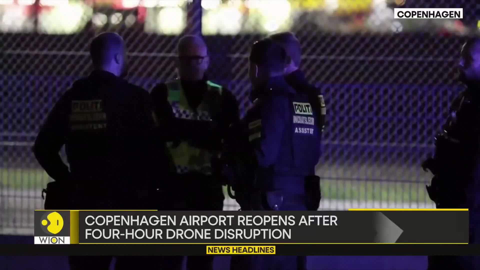 Several uniformed officers stand close together, illuminated by a bluish light. The text at the bottom of the screen, from WION, indicates the scene is related to a drone disruption at Copenhagen Airport.
