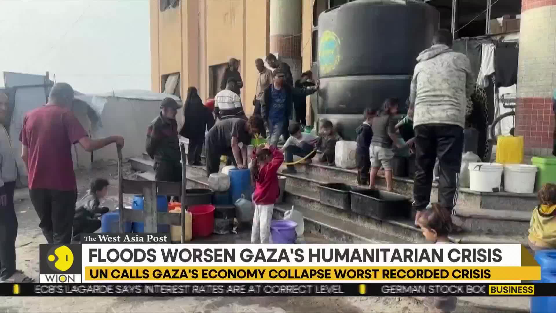 People are gathered around a large water tank, filling buckets and containers. Children and adults alike are working together on the steps, likely trying to collect water.
