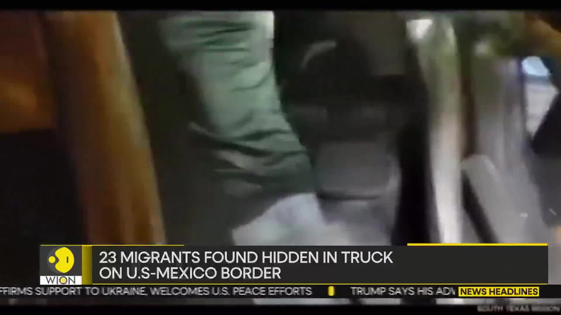 Legs in green pants and light-colored shoes are stepping out of a vehicle. The scene is being reported by WION, with a headline about migrants found hidden in a truck on the U.S.-Mexico border.
