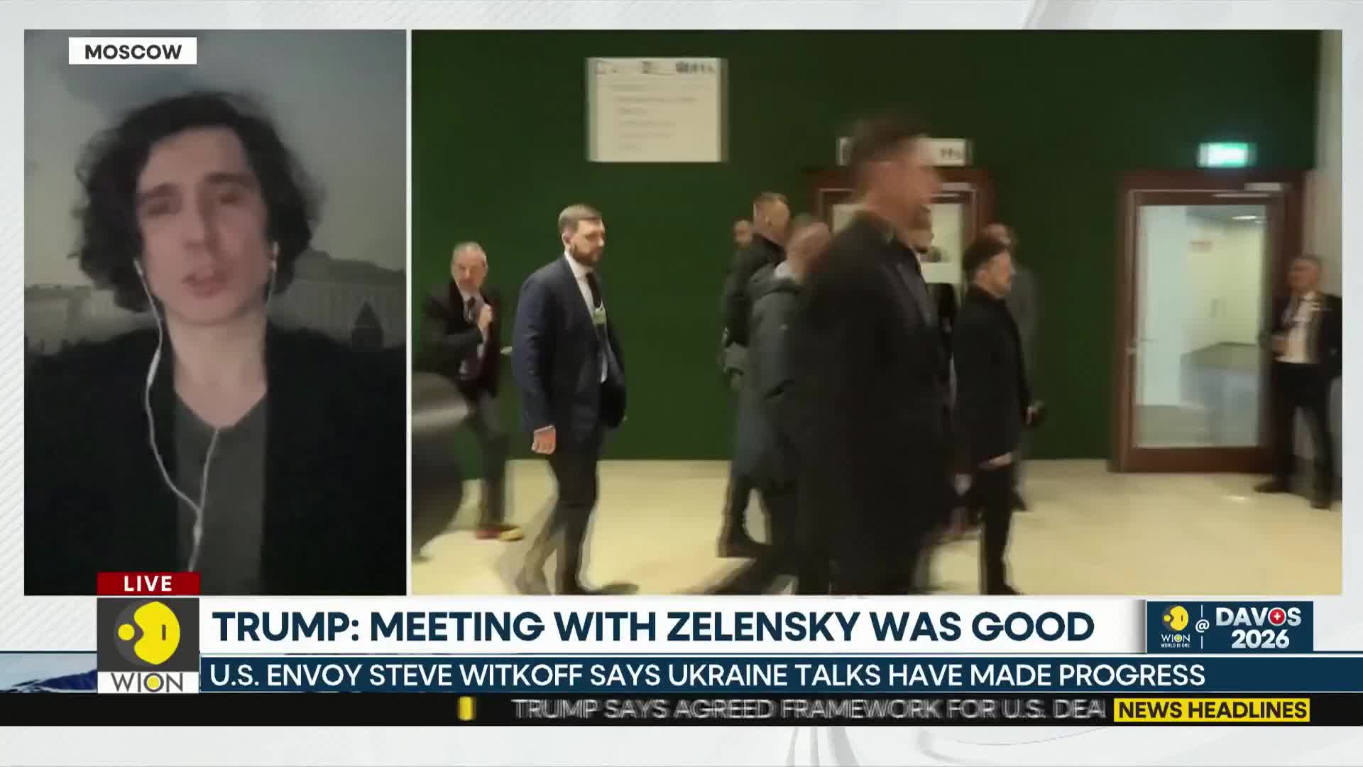 A group of men in suits walk through a hallway, their footsteps echoing on the polished floor. One man, with a beard and dark suit, strides ahead, while others follow closely behind.