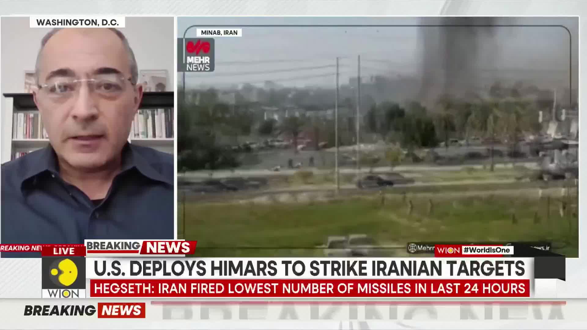 A plume of smoke rises from what looks like an industrial area in Minab, Iran. Cars move along a road in the foreground, with trees and buildings behind them.