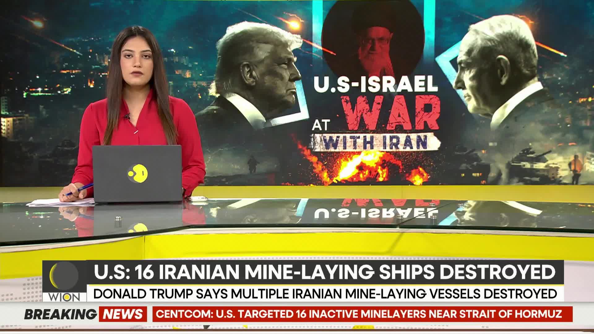 A news anchor in a red top reports from a studio, her laptop open before her. Behind her, a large screen displays images of Donald Trump and Benjamin Netanyahu, with "U.S.-ISRAEL AT WAR WITH IRAN" emblazoned across it.