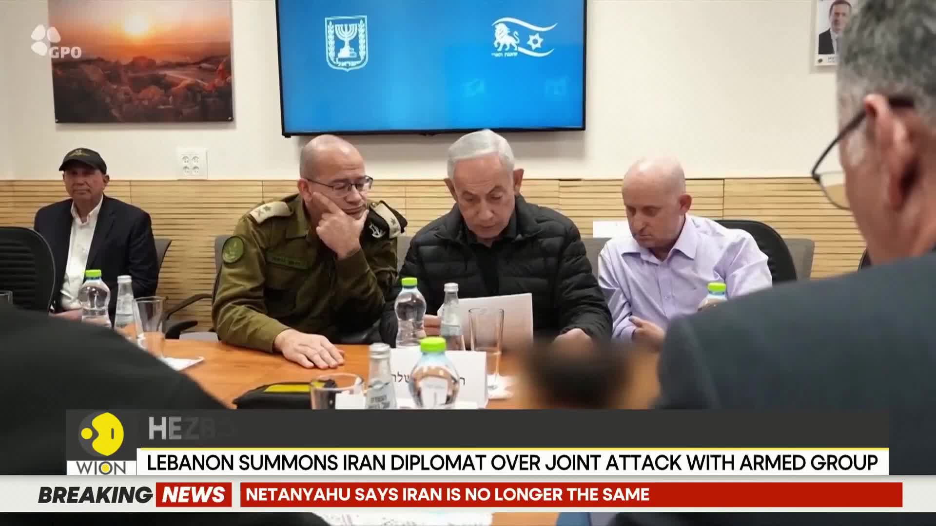 Benjamin Netanyahu, in a dark jacket, leans over a table, his gaze fixed on papers. A man in military uniform, with glasses, rests his chin on his hand, looking thoughtfully to the side.
