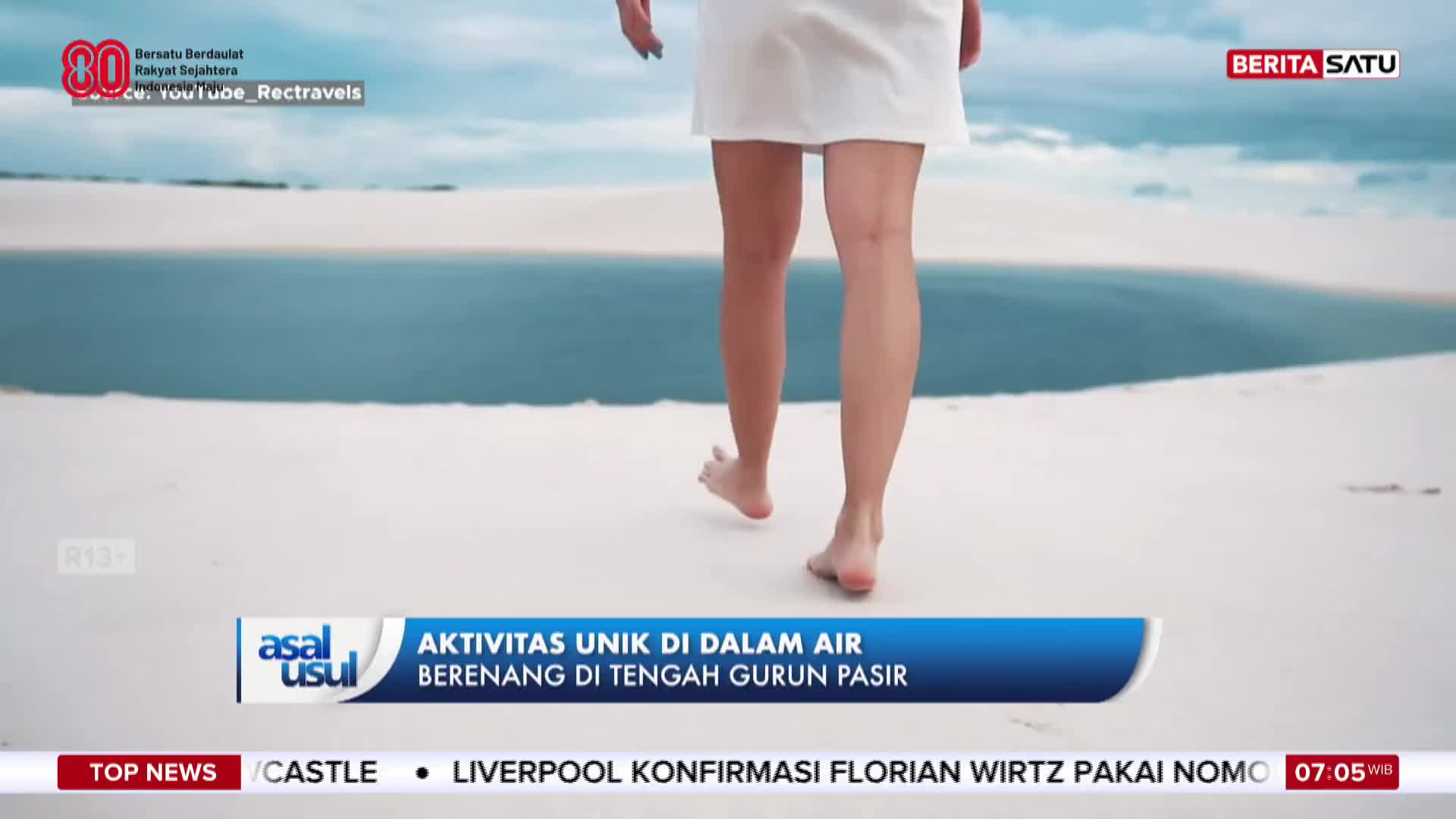 A person in a white dress walks barefoot across the sand, heading toward a body of water. This is part of a segment on BeritaSatu English, highlighting unique activities in Indonesia.
