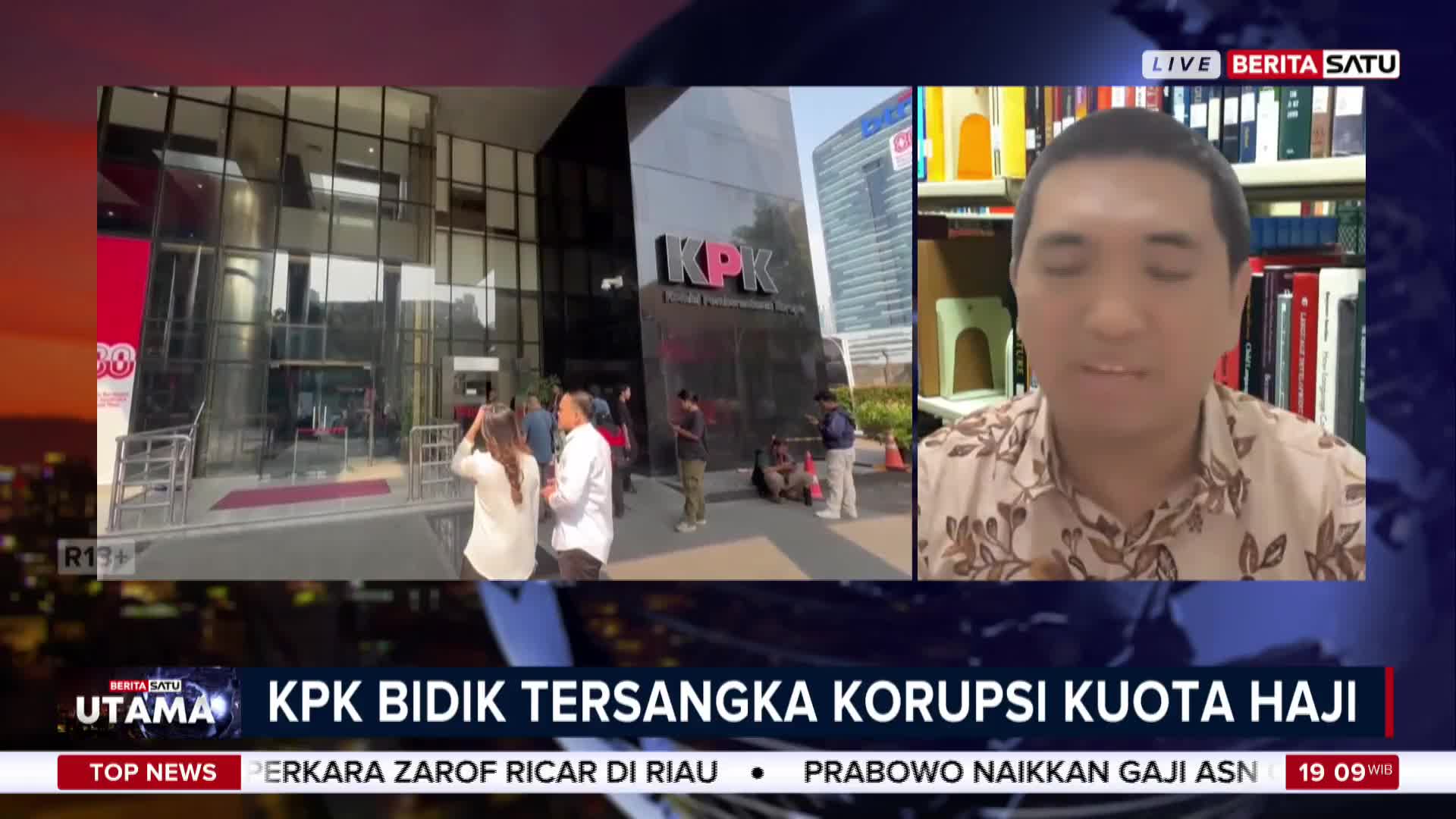 Outside the KPK building in Indonesia, people mill about, while a man on BeritaSatu English discusses the investigation into the Hajj quota corruption case. The news anchor is in a room with bookshelves behind him.
