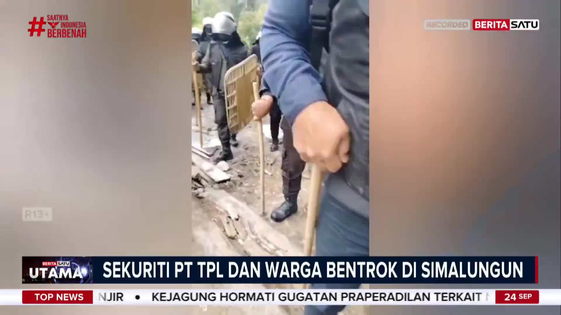 A line of security personnel, some with shields, stand on a rough surface, holding batons. The BeritaSatu English news banner at the bottom states a clash between PT TPL security and local residents in Simalungun, Indonesia.
