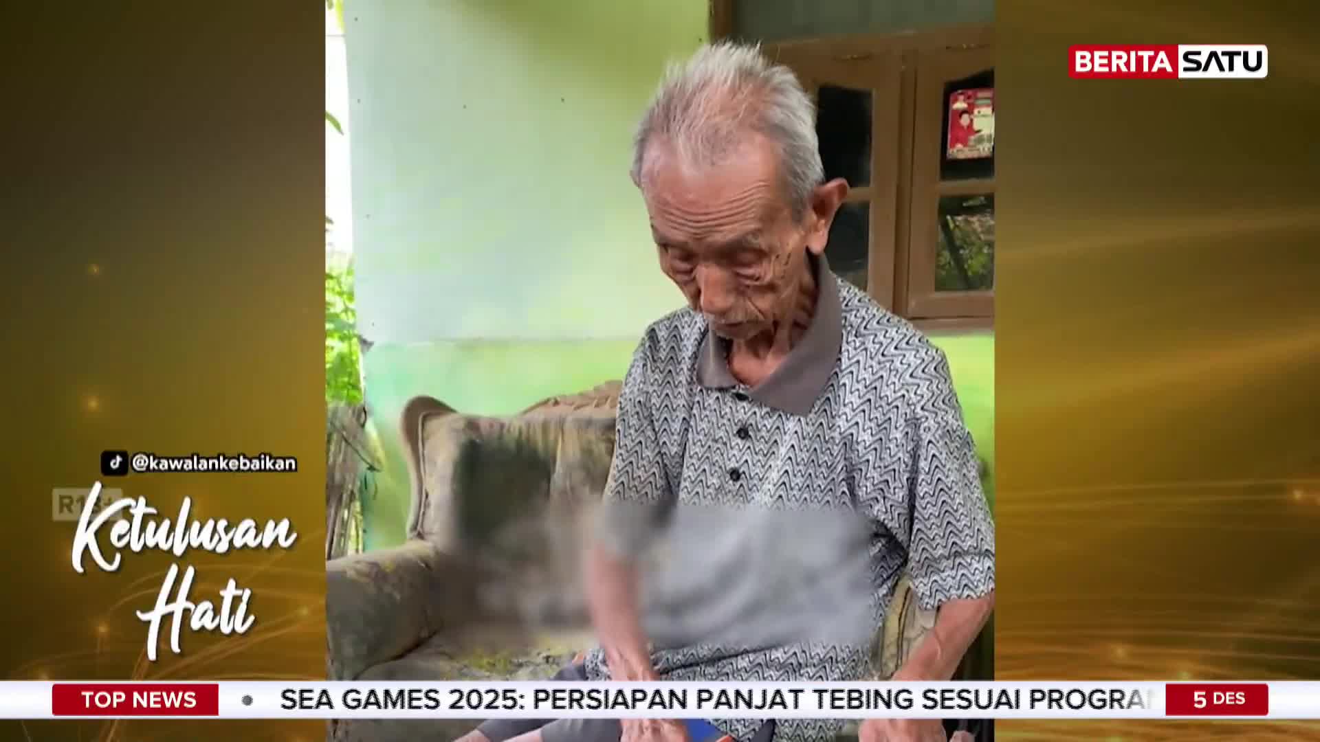 An elderly man, seated on a worn sofa, looks down, his hands obscured by a blur. The BeritaSatu English logo is visible, and the screen indicates the news is from Indonesia.
