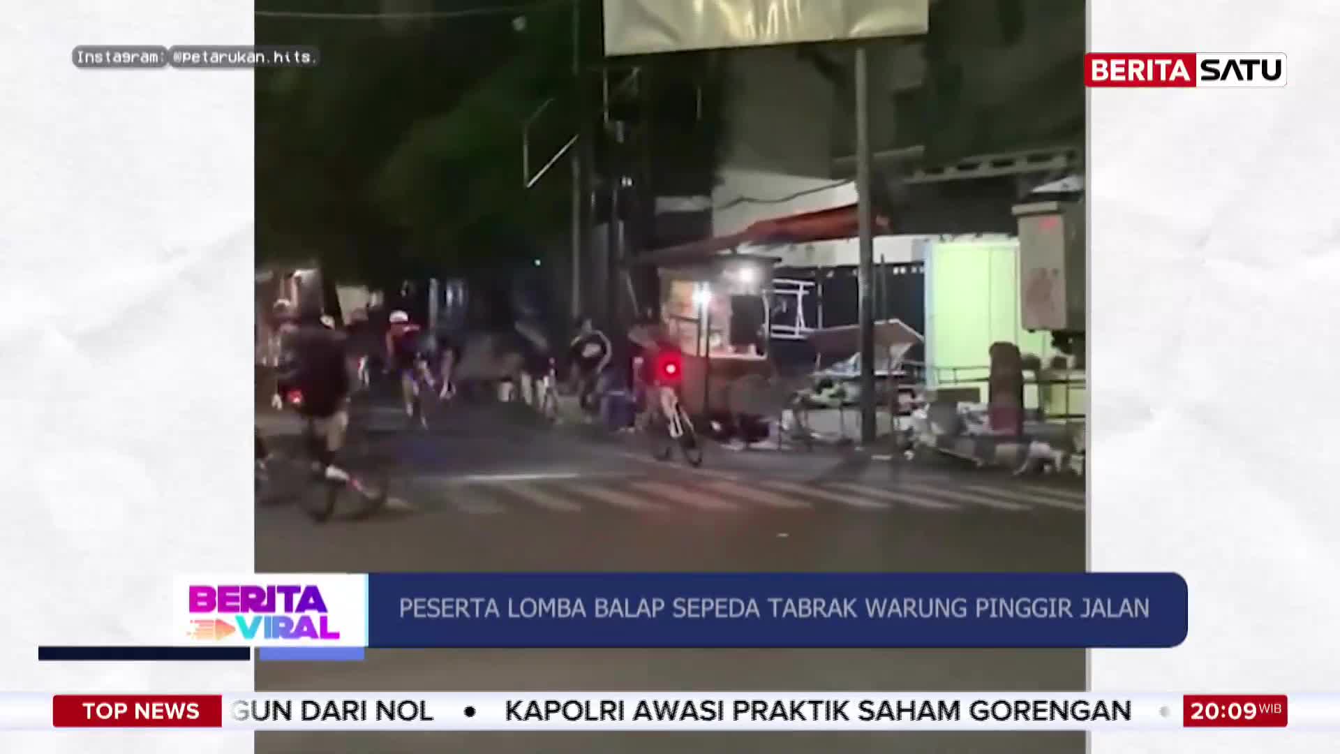 A group of cyclists races down a street at night, some swerving near roadside stalls. One cyclist, wearing a helmet and dark clothing, is in the foreground, his bicycle's red taillight visible.