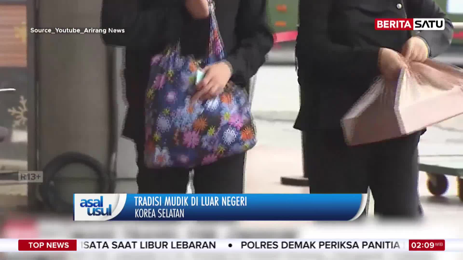 A person in a black jacket carries a colourful floral tote bag. Another person nearby holds a light-colored shopping bag.