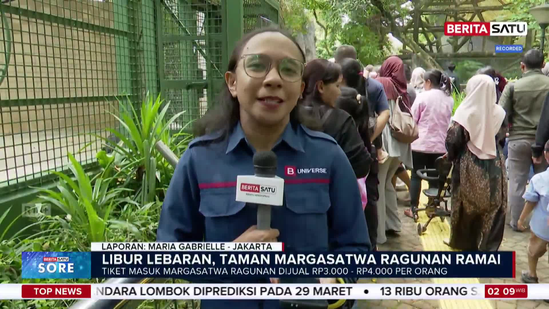 A reporter stands in front of a crowd of people queuing at Ragunan Zoo. The Lebaran holiday has brought many visitors to the popular Jakarta attraction.