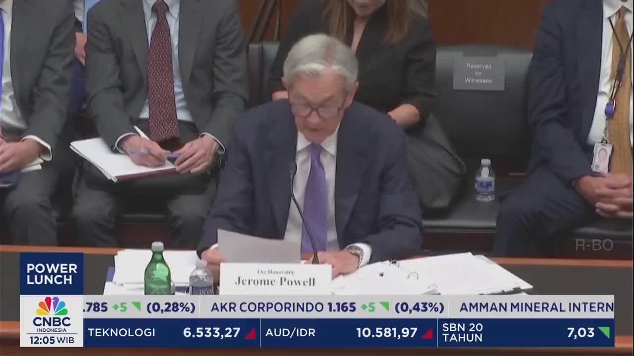 Jerome Powell, identified on the CNBC Indonesia broadcast, reads from a paper at a table. Other people in suits sit around him, some taking notes.
