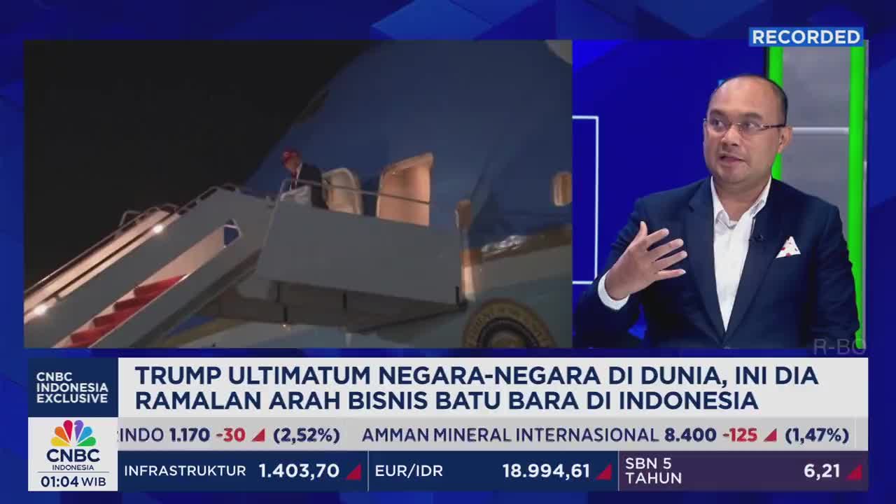 On CNBC Indonesia, a man in a suit gestures animatedly while discussing business in Indonesia. Across the screen, a person is seen descending the steps of a plane, possibly Air Force One.
