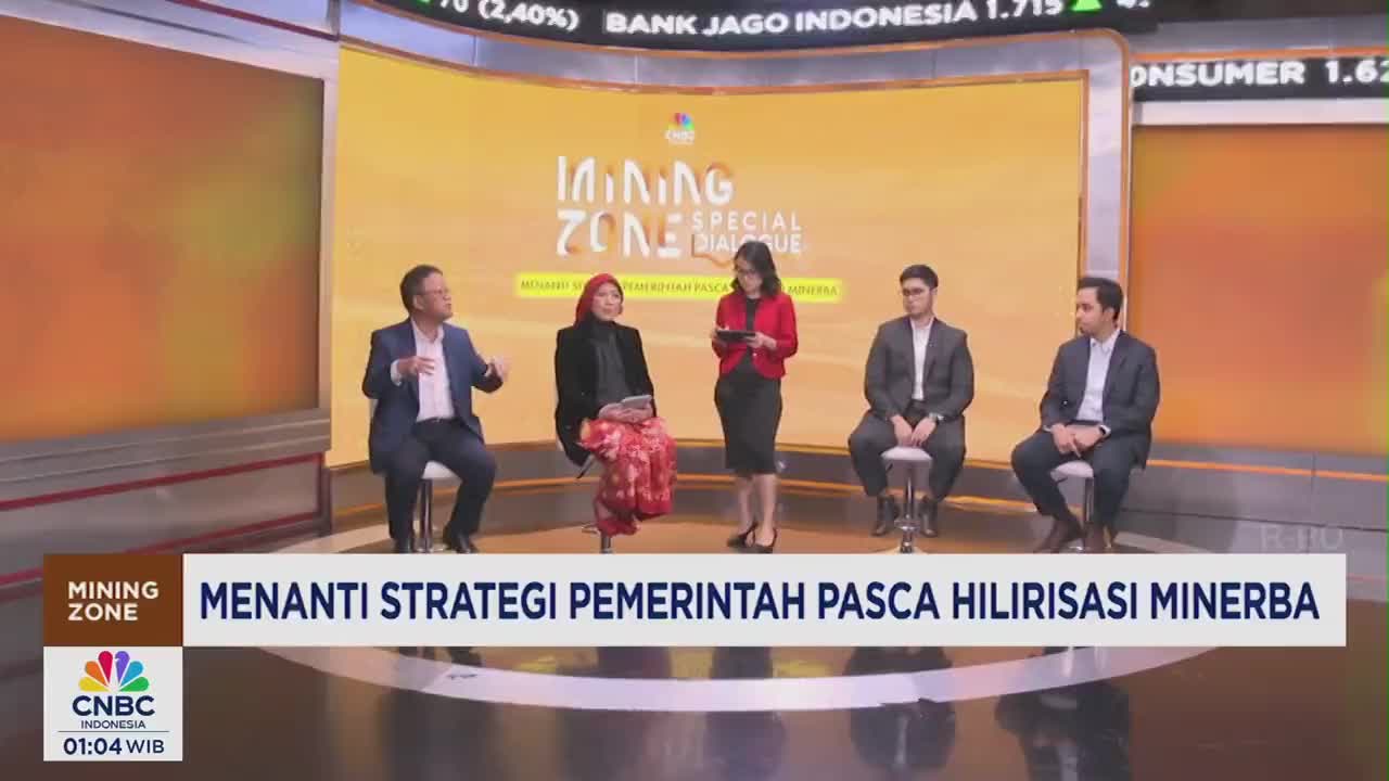 Four people sit on stools, while a woman in a red jacket stands holding a tablet. The CNBC Indonesia logo is visible, and the broadcast is discussing mining strategy.
