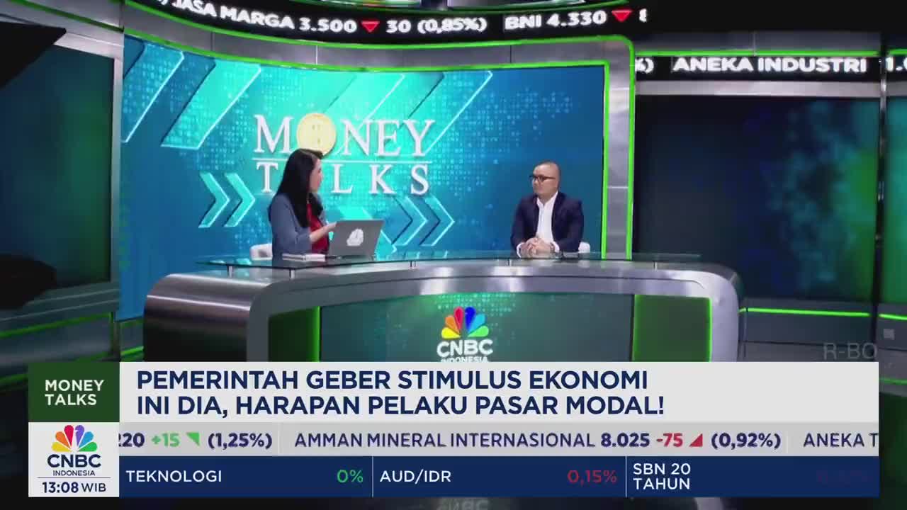 Two people sit at a desk on the set of CNBC Indonesia's "Money Talks" program, discussing the Indonesian government's economic stimulus. The lower third displays stock market data and the program's title.
