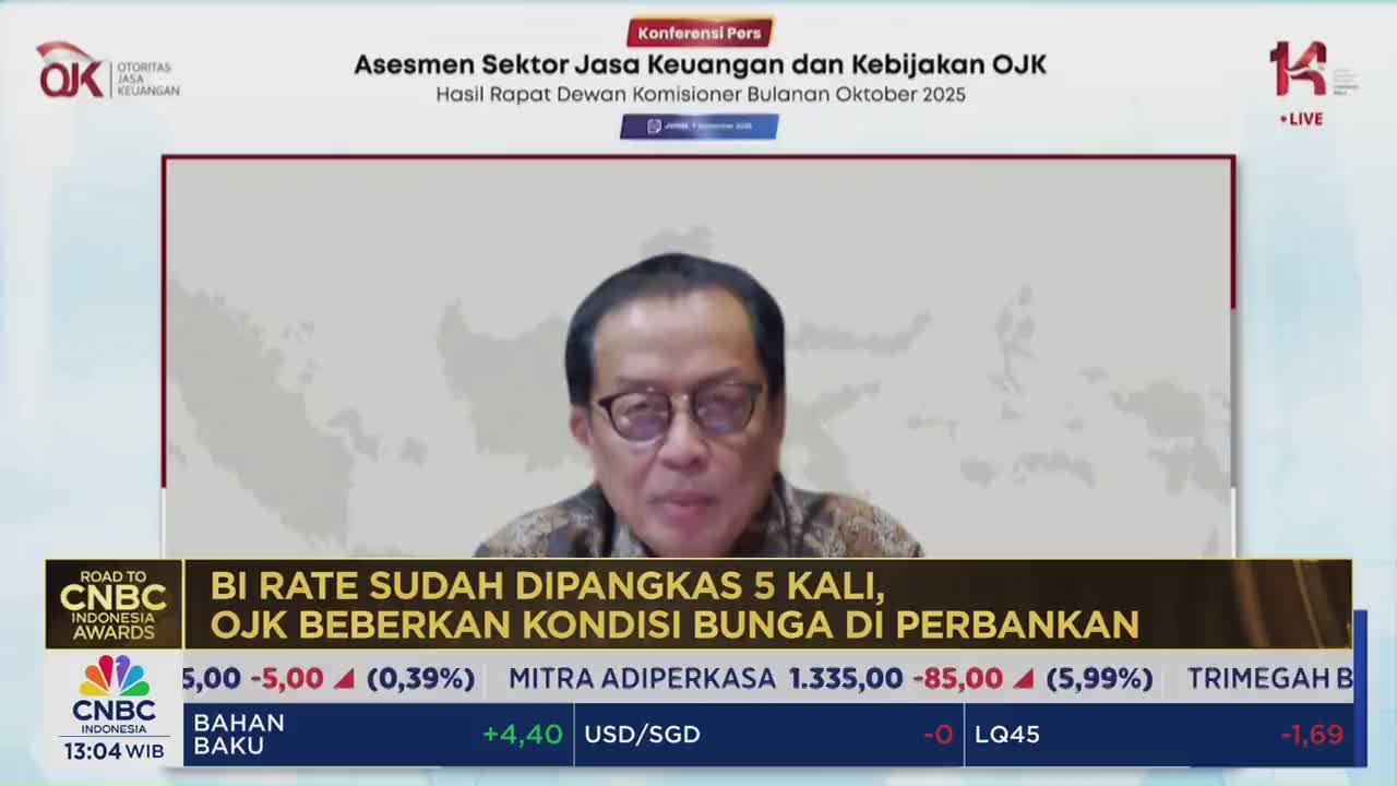 A man in glasses speaks into a camera, his image broadcast on CNBC Indonesia. Below, financial data and headlines scroll across the screen.
