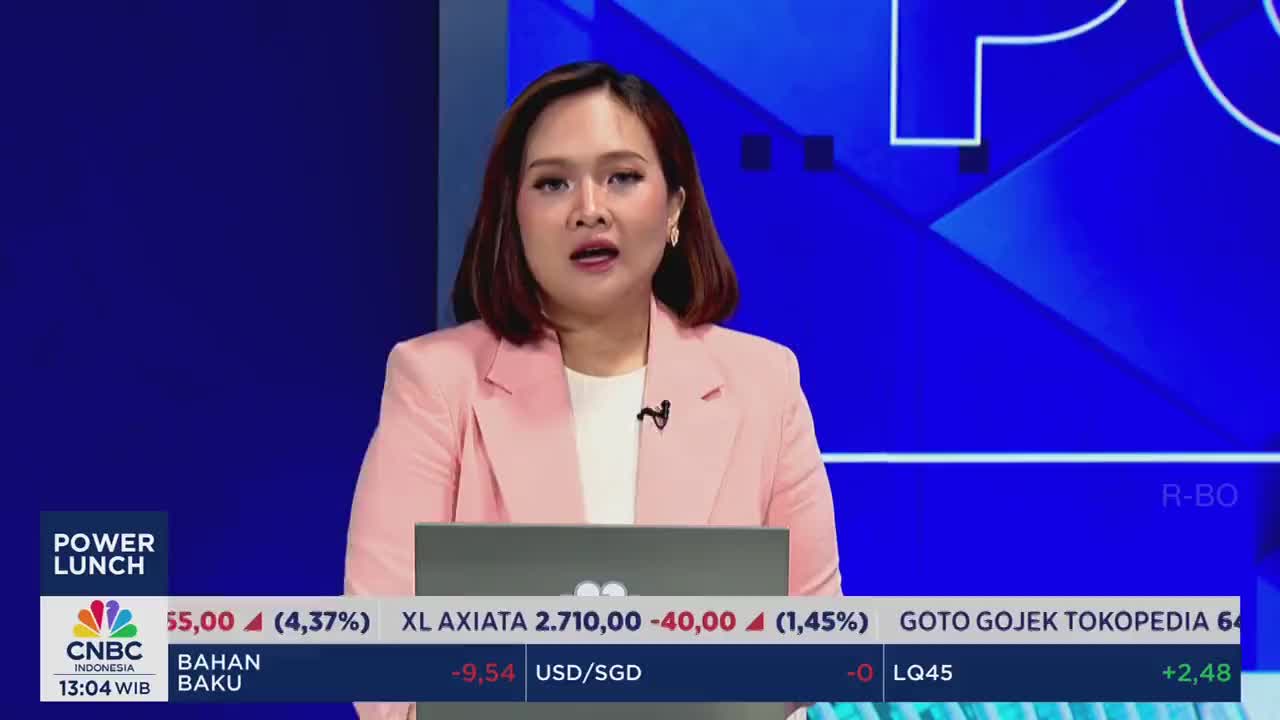 A woman in a pink blazer speaks directly to the camera, likely delivering financial news. The CNBC Indonesia logo and stock market data are visible on the screen below.
