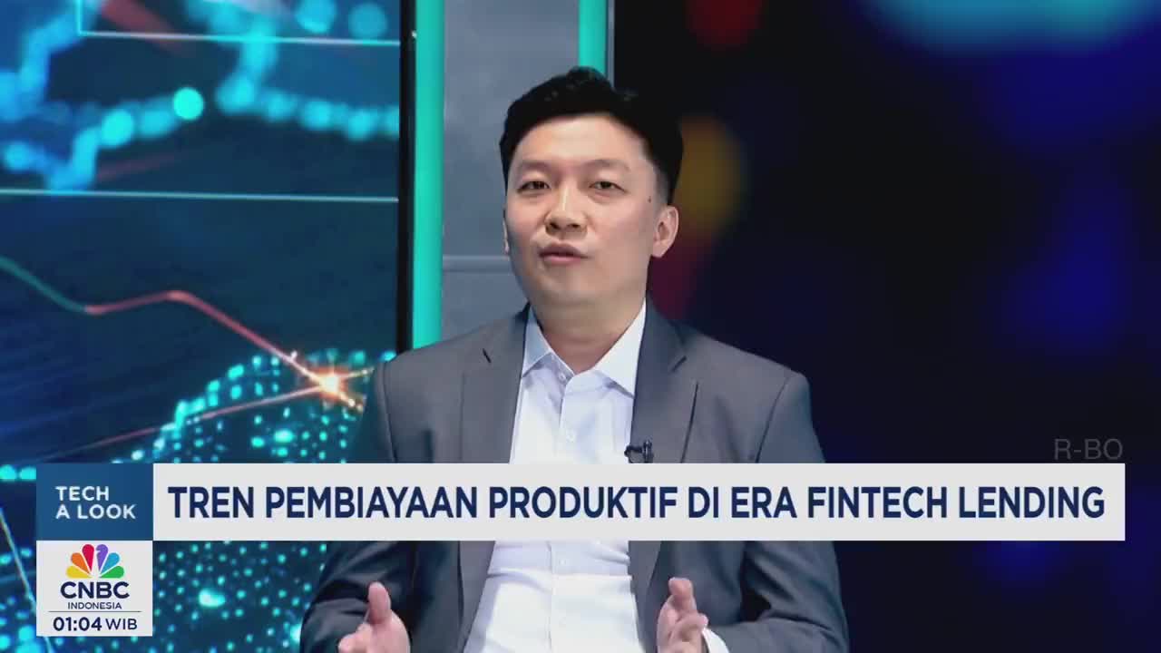 A man in a gray suit speaks directly to the camera, his hands gesturing slightly. The CNBC Indonesia logo and a title about fintech lending are displayed below.
