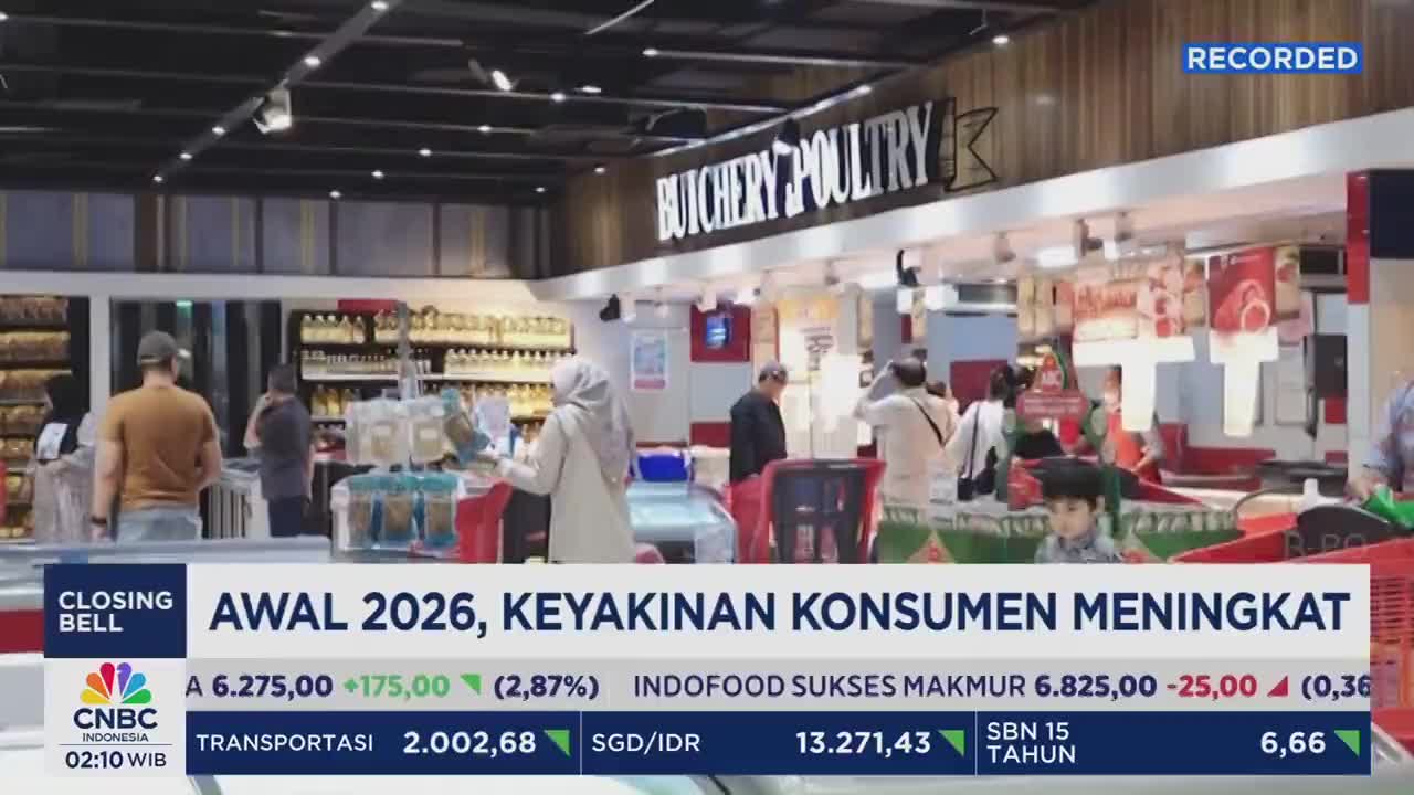 People browse the aisles of a brightly lit supermarket in Indonesia. A CNBC Indonesia graphic overlays the scene, showing stock market data.