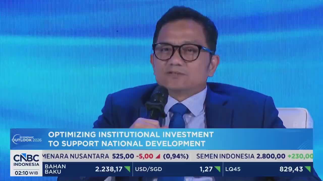 A man in a suit speaks into a microphone at a CNBC Indonesia economic forum. The screen behind him displays "Optimizing Institutional Investment to Support National Development."