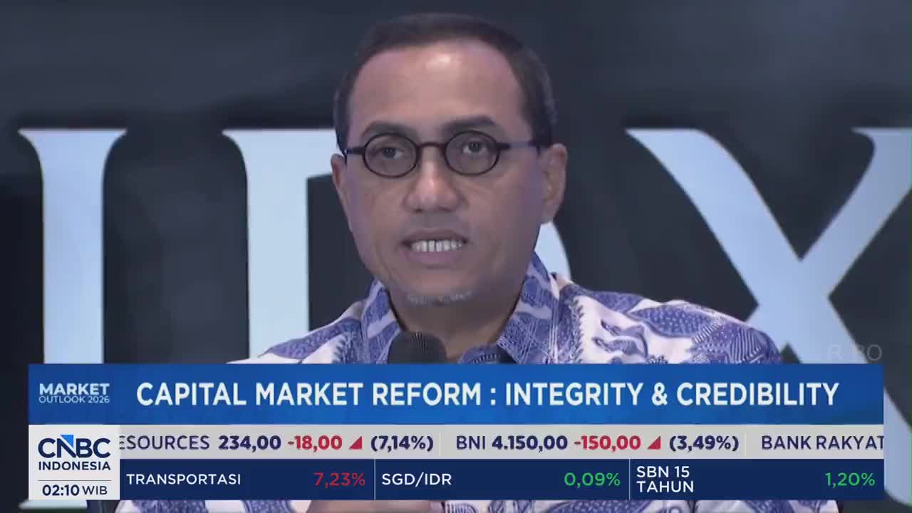 A man in glasses and a blue patterned shirt speaks into a microphone, with a CNBC Indonesia banner below him. The banner displays "CAPITAL MARKET REFORM : INTEGRITY & CREDIBILITY" and stock market data.