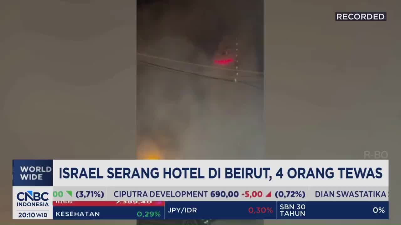Thick smoke billows upwards, obscuring a building where red lights flicker. Below, a CNBC Indonesia chyron announces an Israeli attack on a Beirut hotel, resulting in four deaths.