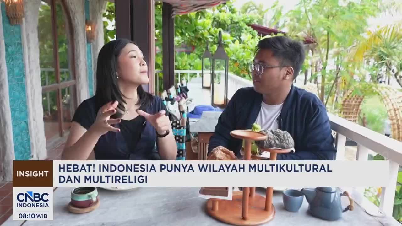 A woman gestures animatedly while speaking to a man across a table. They are seated outdoors in a lush, tropical setting, likely for a CNBC Indonesia broadcast. A woman gestures animatedly while speaking to a man across a table. They are seated outdoors in a lush, tropical setting, likely for a CNBC Indonesia broadcast.