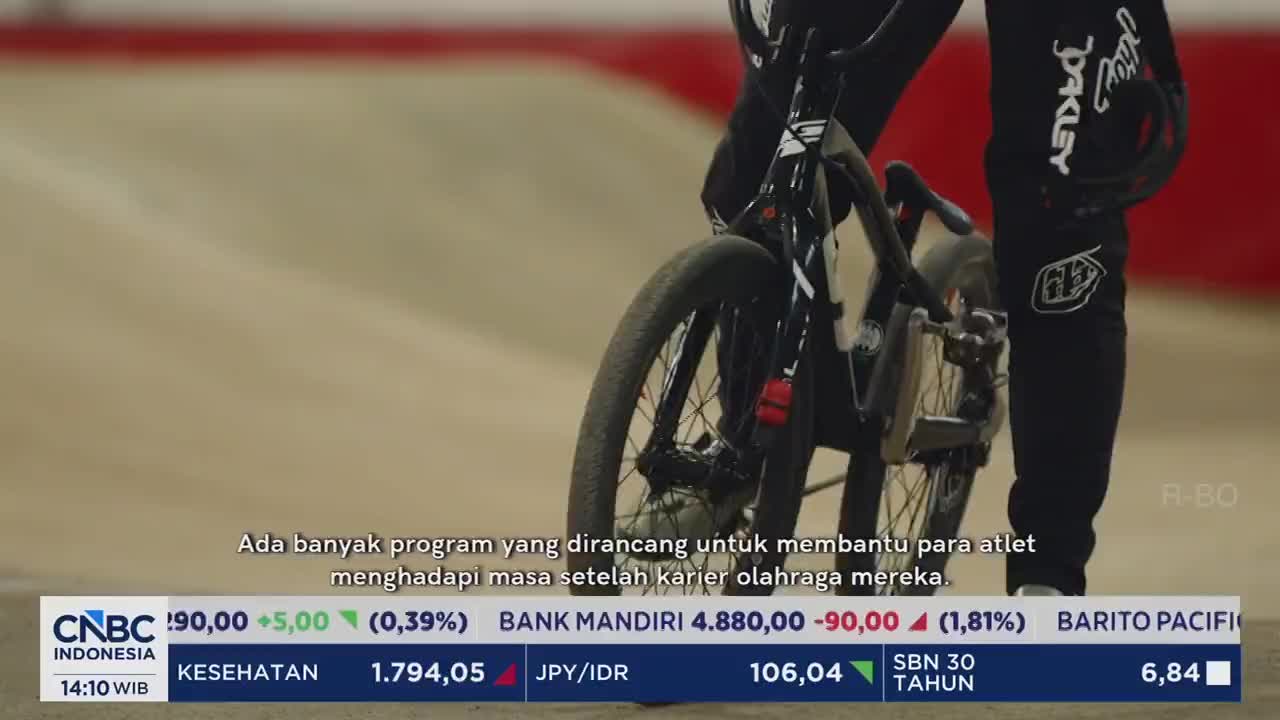 A BMX rider, clad in black gear with Oakley logos, stands beside their bike on a dirt track. Below, a CNBC Indonesia ticker displays financial data. A BMX rider, clad in black gear with Oakley logos, stands beside their bike on a dirt track. Below, a CNBC Indonesia ticker displays financial data.