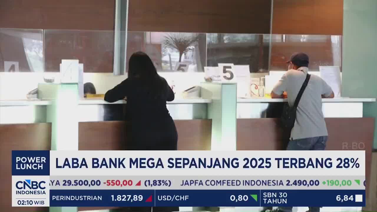 A customer, wearing a dark shirt and jeans, leans forward at a bank counter. Another person, in a light grey shirt and cap, stands at a separate counter. A customer, wearing a dark shirt and jeans, leans forward at a bank counter. Another person, in a light grey shirt and cap, stands at a separate counter.