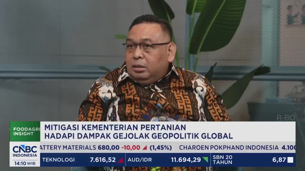A man in a patterned shirt speaks intently, his glasses reflecting the studio lights. Below him, a CNBC Indonesia chyron displays stock market data and the title "MITIGASI KEMENTERIAN PERTANIAN HADAPI DAMPAK GEJOLAK GEOPOLITIK GLOBAL."