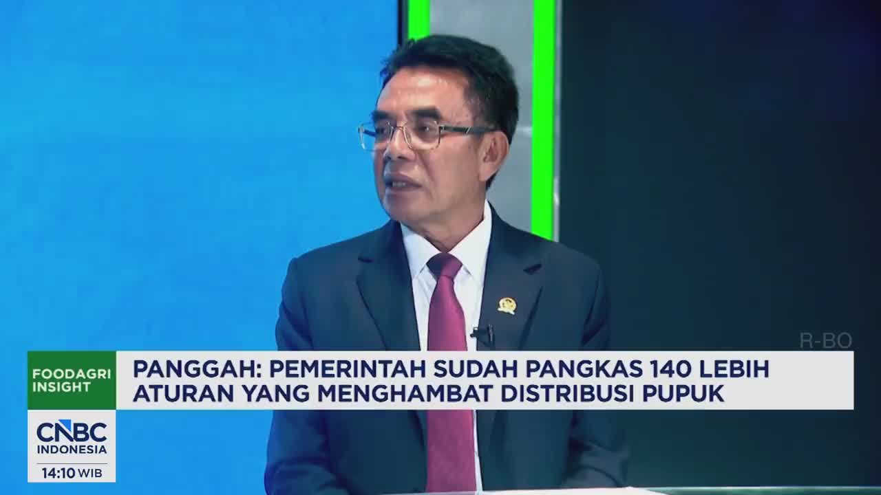 A man in a suit and tie speaks, his glasses reflecting the studio lights. Text overlays from CNBC Indonesia and FoodAgri Insight appear on screen, indicating a discussion about government regulations.