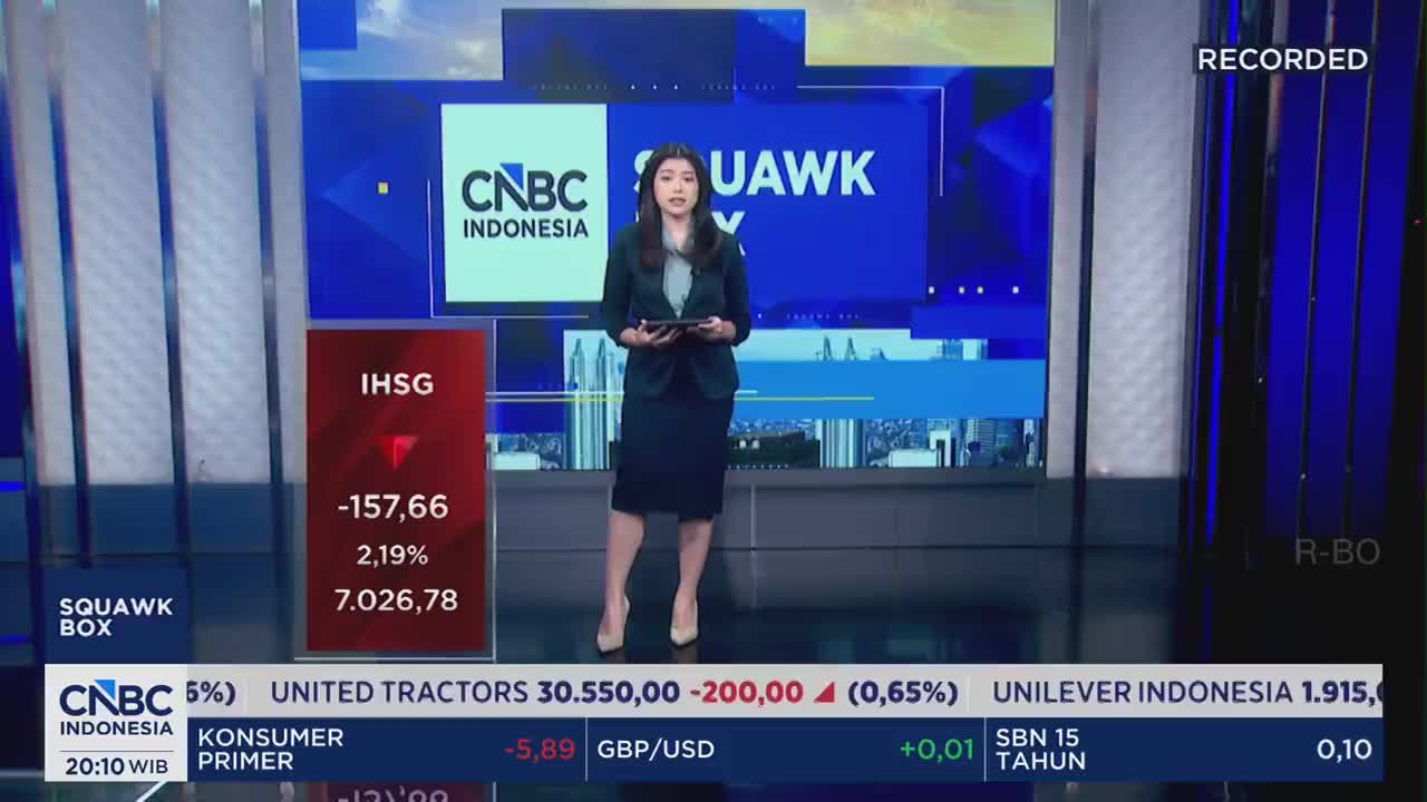 A woman stands on a studio floor, holding a tablet, with the CNBC Indonesia logo behind her. A red marker on a screen shows the IHSG index down by 157.66 points. A woman stands on a studio floor, holding a tablet, with the CNBC Indonesia logo behind her. A red marker on a screen shows the IHSG index down by 157.66 points.