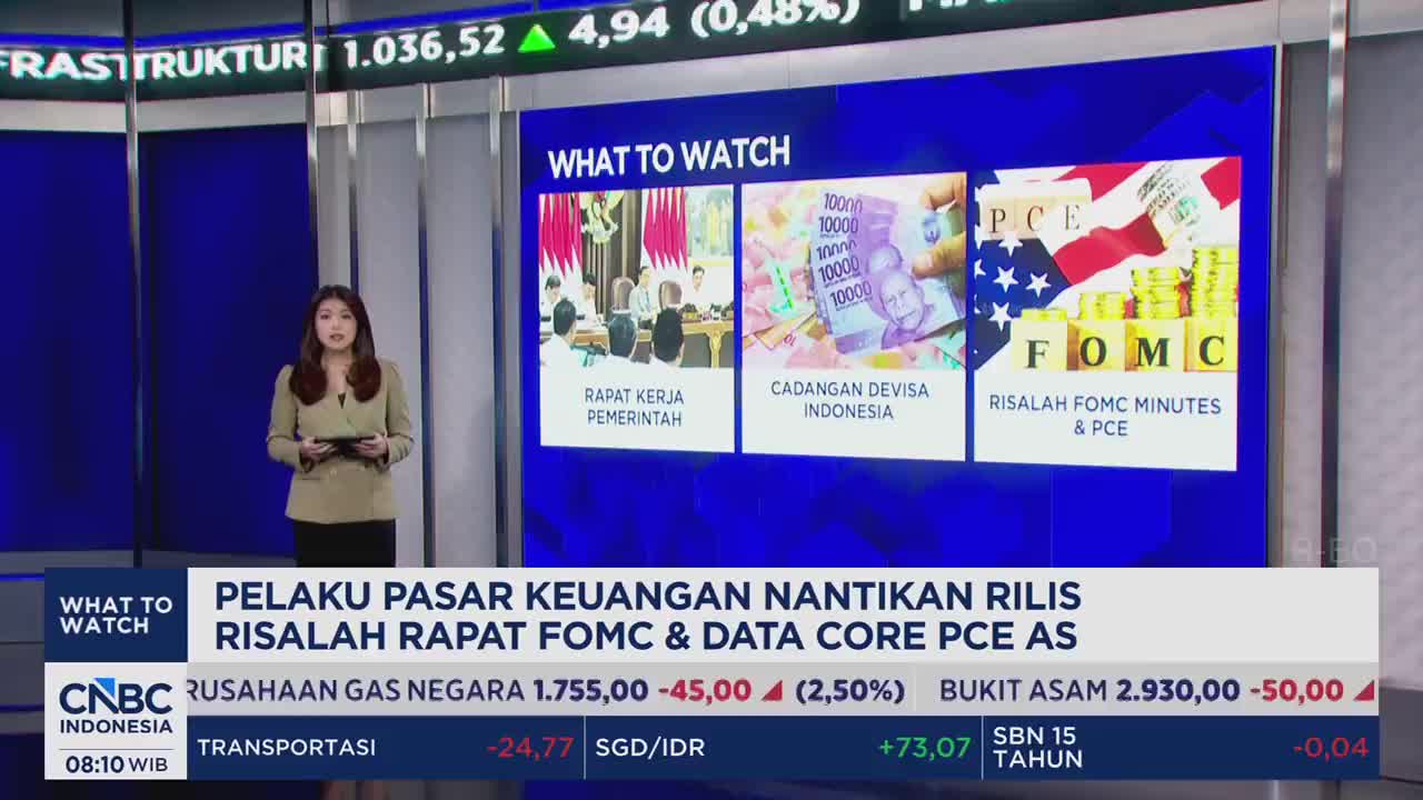 A woman stands before a screen displaying financial news from CNBC Indonesia. The screen highlights "What to Watch," featuring images of Indonesian Rupiah and U.S. economic indicators. A woman stands before a screen displaying financial news from CNBC Indonesia. The screen highlights "What to Watch," featuring images of Indonesian Rupiah and U.S. economic indicators.